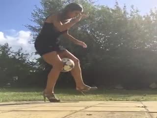 Девушка в платье и на каблуках набивает мяч